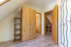 Een kamer met een houten garderobe, een houten deur en een kapstok.