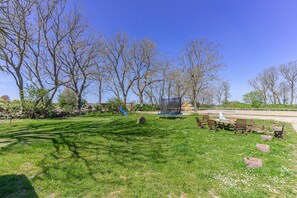 A grassy outdoor area with a trampoline, wooden chairs, and a swing set. - Pferdehof Königsstuhl - Apartment 5 Friese - Holidays at the riding stable - Apartment (Lohme)