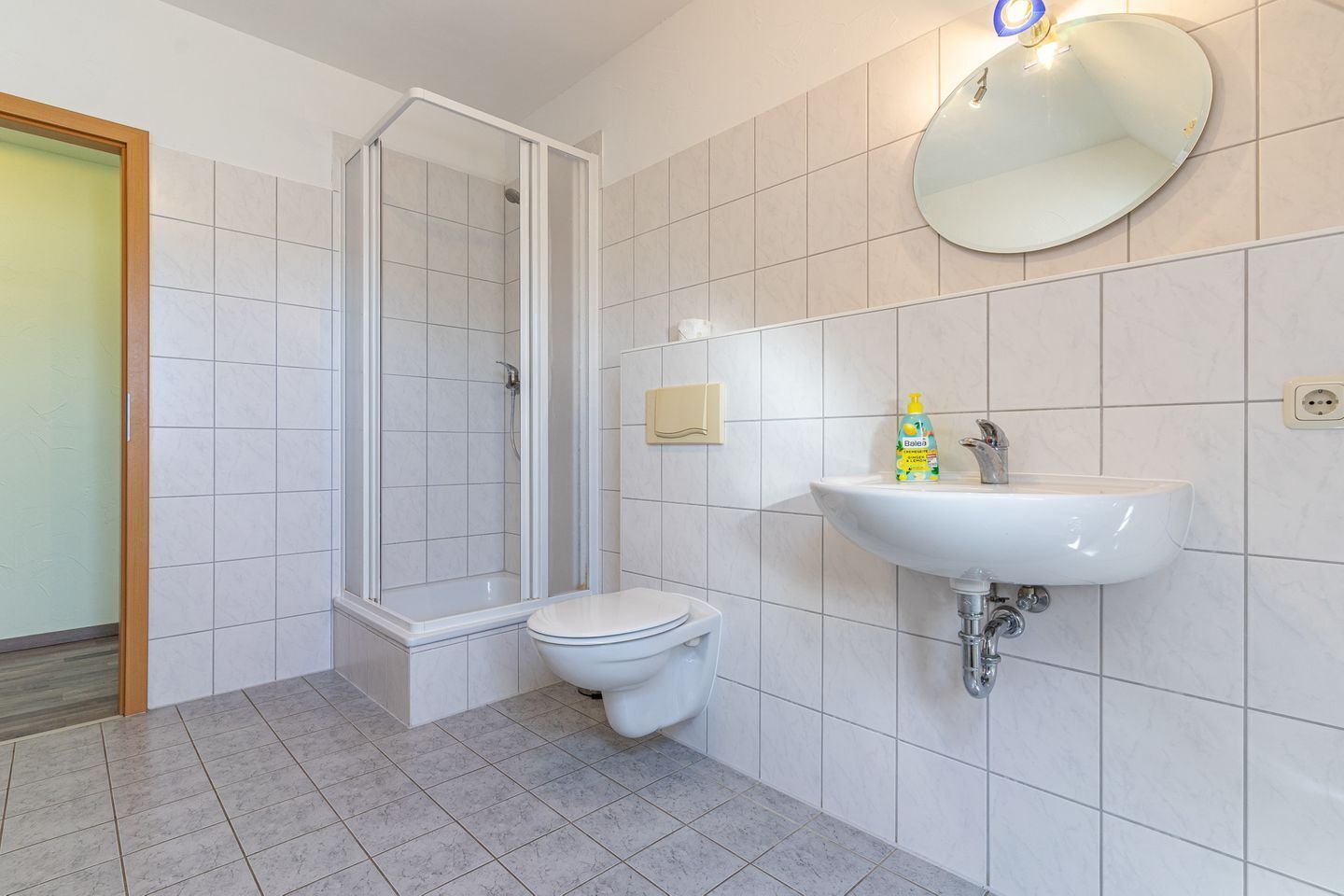 Ein Badezimmer mit Dusche, Toilette, Waschbecken und Spiegel.