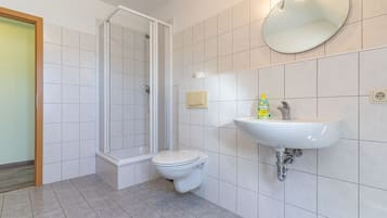 Ein Badezimmer mit Dusche, Toilette, Waschbecken und Spiegel.