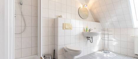A modern bathroom with a shower, toilet, sink, and a towel rack.
