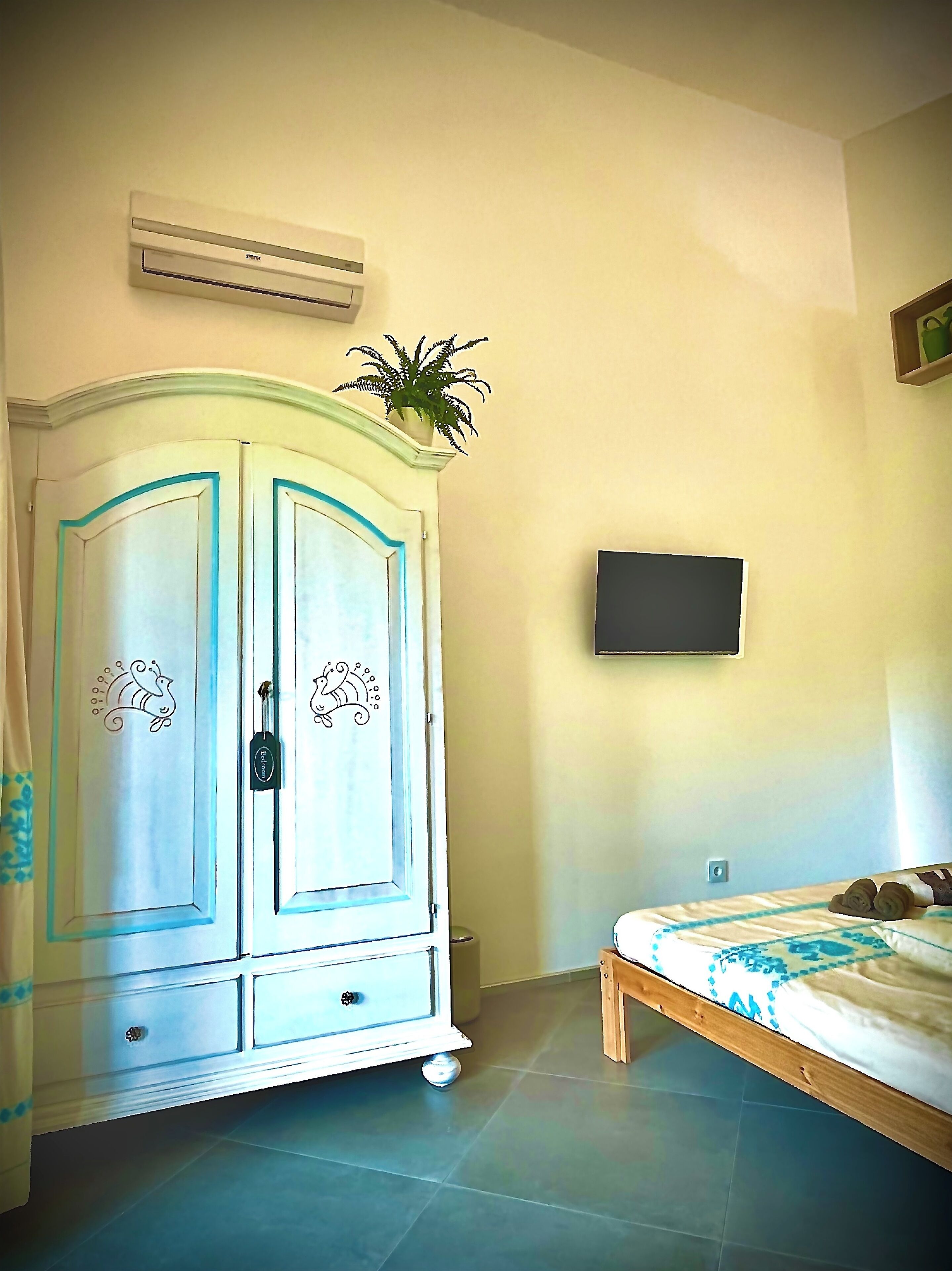 Een slaapkamer met een bed, een kledingkast, een airconditioner en een televisie aan de muur.