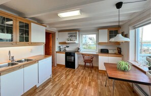 A modern kitchen with wooden cabinets, a dishwasher, and a window overlooking a scenic view.