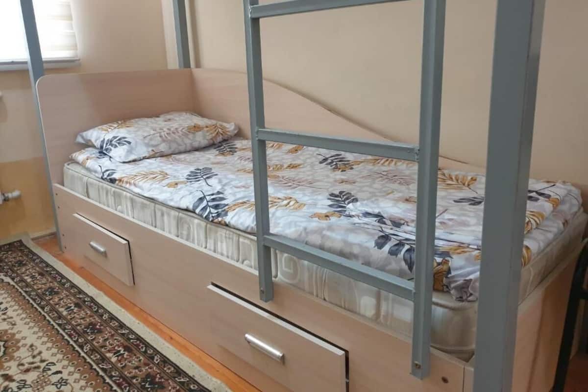 Una cama litera con una colcha estampada de flores, piso de madera y una alfombra con diseño.