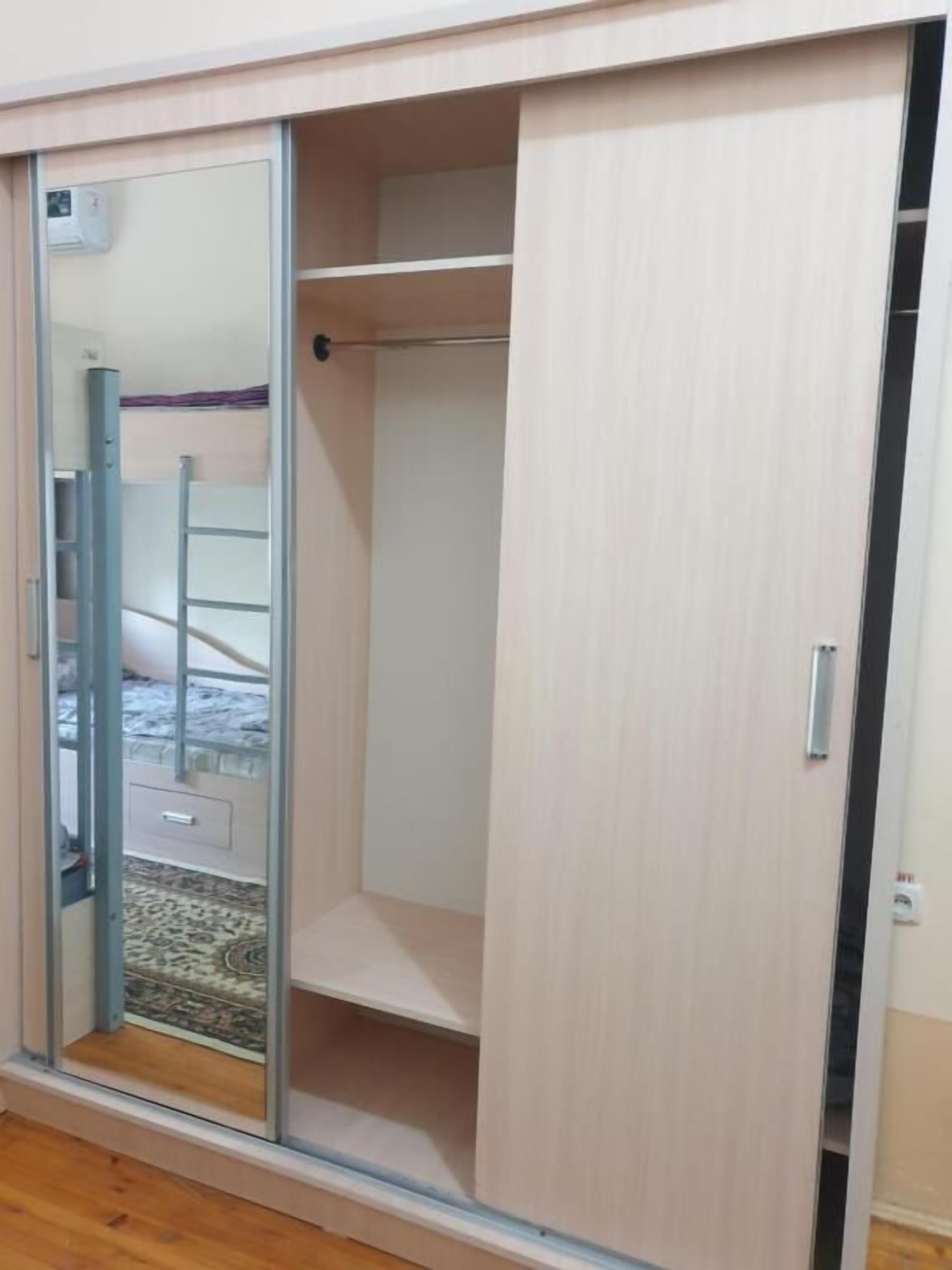 Een kamer met een schuifdeurkast, een bed met een beddengoed met een patroon en een zichtbare stopcontact.