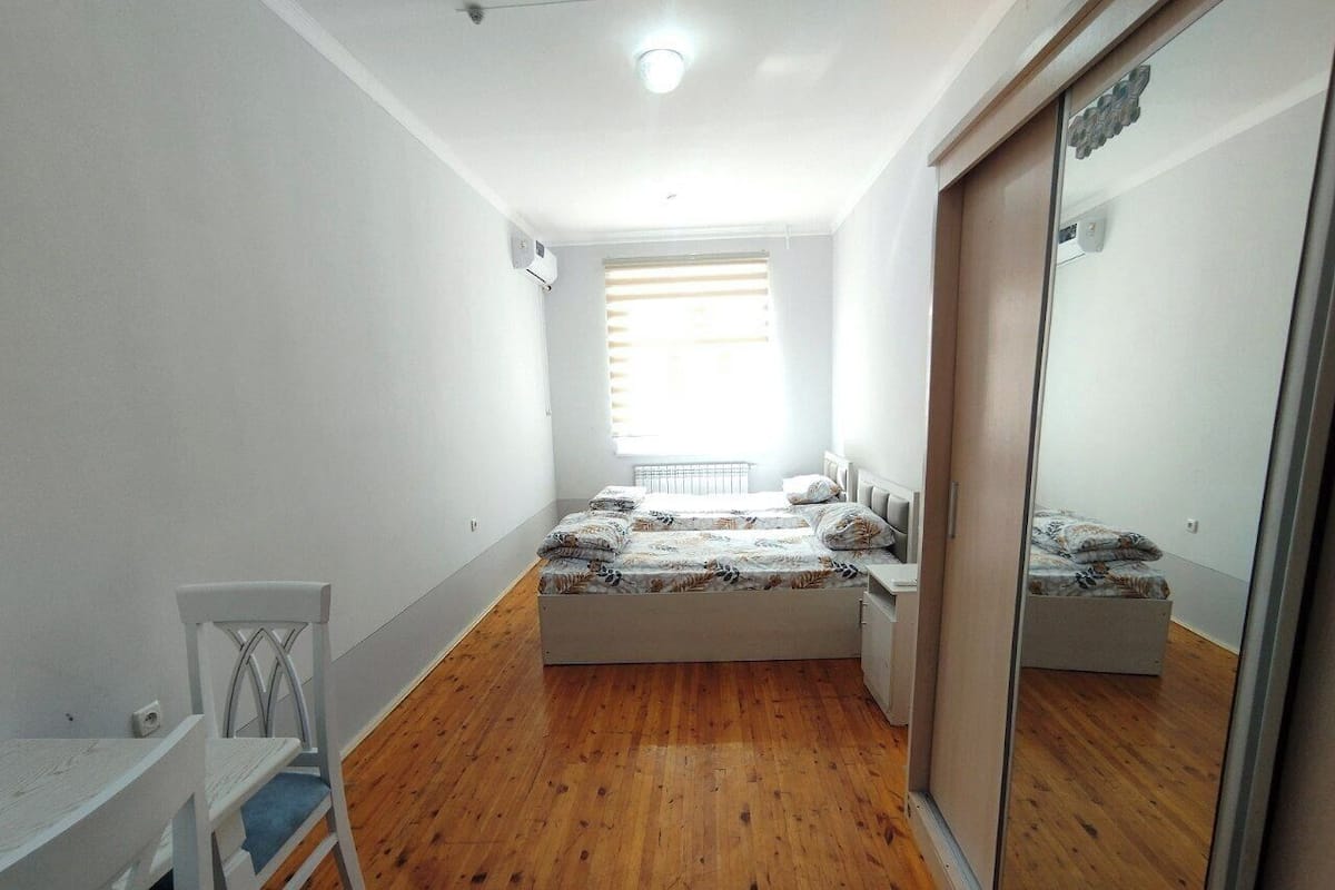 Un dormitorio con cama, una silla, un escritorio y una ventana.
