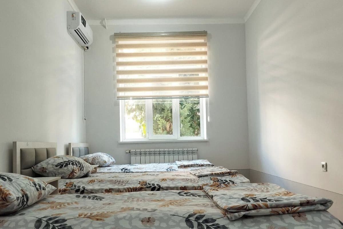 Un dormitorio con una cama grande, un radiador, una ventana con persianas y un equipo de aire acondicionado.