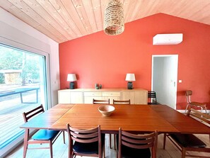 A dining area with a wooden table, chairs, a central bowl, and two lamps on a cabinet. - Villa Mantra by Agence Bru - 709131 (Lacanau)