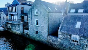 Un bâtiment en pierre, sur lequel on peut lire l’inscription « Lerwick Boating Club », est situé à côté d’un cours d’eau.
