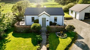 A white house with a stone foundation, a front door, and a small porch.