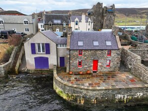 A stone building with a red door, a small window, and a stone wall.