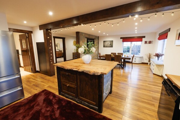 A kitchen with a central island, wooden flooring, and a stone wall.