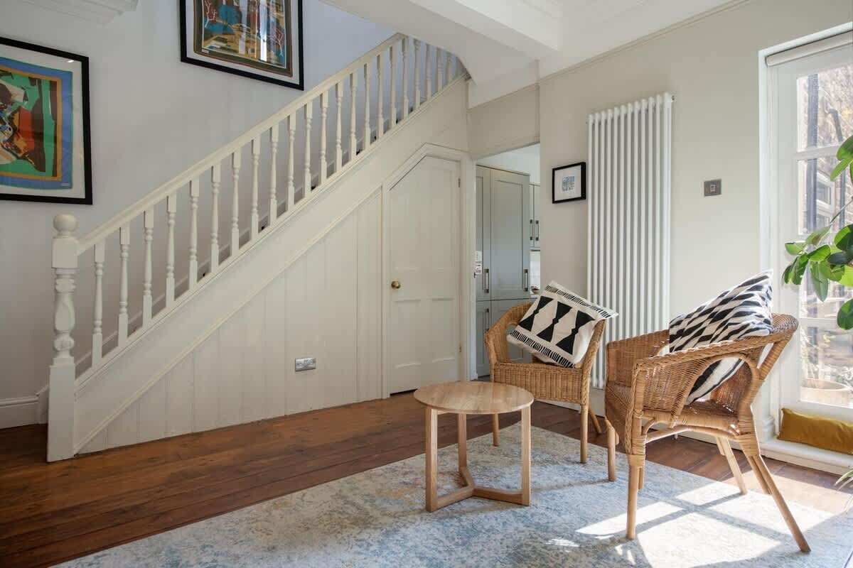 Eine Treppe mit weißen Balustern, ein Korbstuhl mit Kissen in ZEBRA-Muster und ein kleiner runder Tisch auf einem gemusterten Teppich.