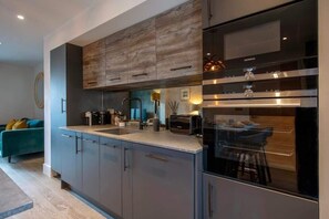 Una cucina moderna con mobili grigi, un frigorifero in acciaio inossidabile e un forno integrato.