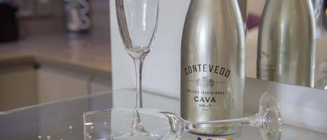 A bottle of Conteveddo Cava Brut wine, a glass, and a teapot on a reflective surface.