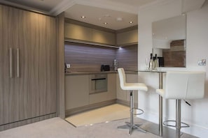 Une cuisine moderne dotée d’un four encastré, d’un coin bar avec des tabourets et d’un grand miroir.