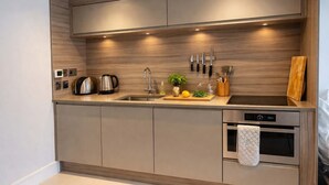 Una cucina moderna con forno integrato, lavello e piano di lavoro con diversi elettrodomestici e utensili.