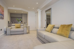 Ein modernes Wohnzimmer mit einer Couch, einem Couchtisch und einer Küche im Hintergrund.
