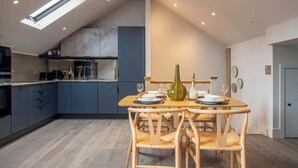 Een moderne keuken met donkere kastjes, een dakraam en een eethoek met een houten tafel en stoelen.