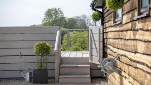 Een houten gebouw met een trap naar een balkon, een bloempot en een hangende bal.