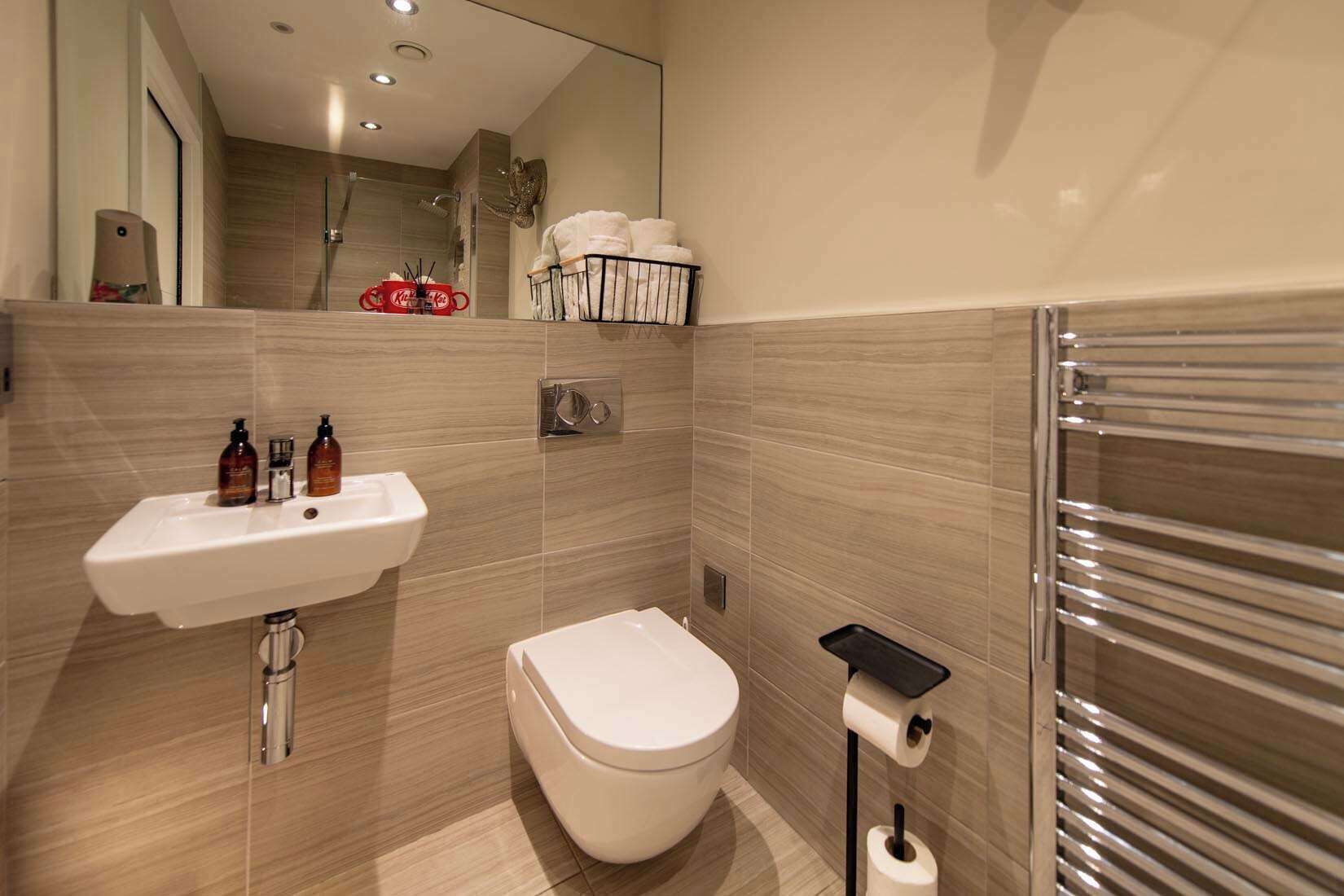 A modern bathroom with a sink, toilet, and towel rack.