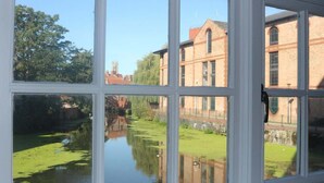 Une vue à travers une fenêtre, avec le reflet d’un immeuble et d’un canal.