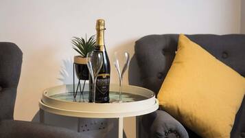 A room with a round table, a bottle of champagne, and two glasses.