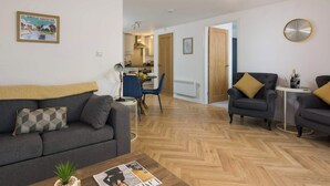 A modern living room with a sofa, armchairs, a coffee table, and a dining area with chairs and a table. - The Aura Suite - Stylish Apartment Near York Minster Free Parking (Layerthorpe)
