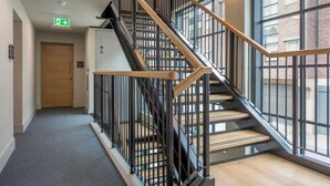 A modern staircase with black railings and wooden steps, leading to an upper floor. - The Palm Suite - Luxury Loft Apartment w/ Private Balcony & City Views (York)