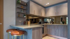 A modern kitchen with a central island, bar stools, and built-in shelves. - The Palm Suite - Luxury Loft Apartment w/ Private Balcony & City Views (York)