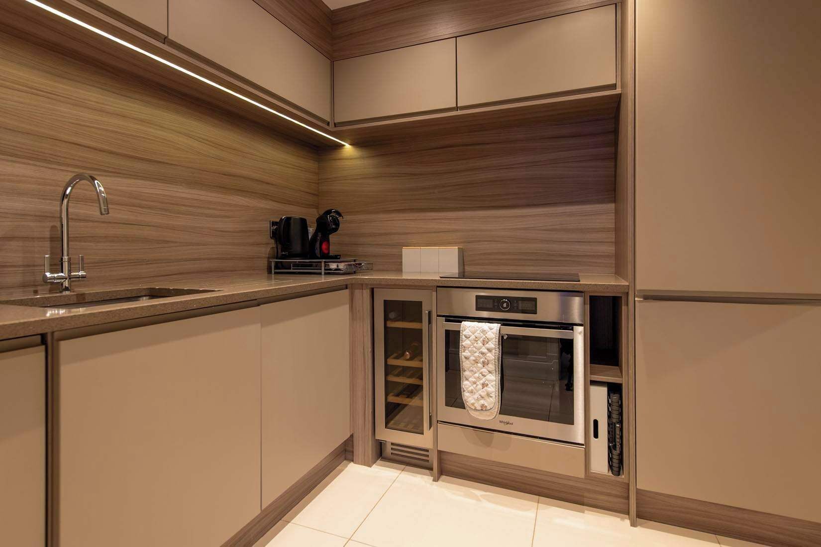 A modern kitchen with a built-in oven, a coffee maker, and a stainless steel sink.