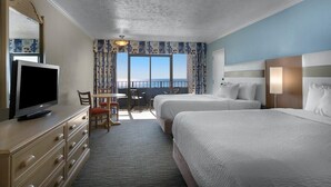 Ett hotellrum med två sängar, en TV, ett skrivbord med en stol och utsikt över havet.