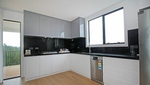 A modern kitchen with white cabinets, a black countertop, and a stainless steel dishwasher. - Your Private Escape with city views (Totara Park)