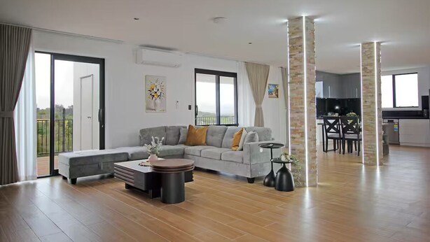 A spacious living area with a grey sofa, a coffee table, and a dining area with a table and chairs. - Your Private Escape with city views (Totara Park)