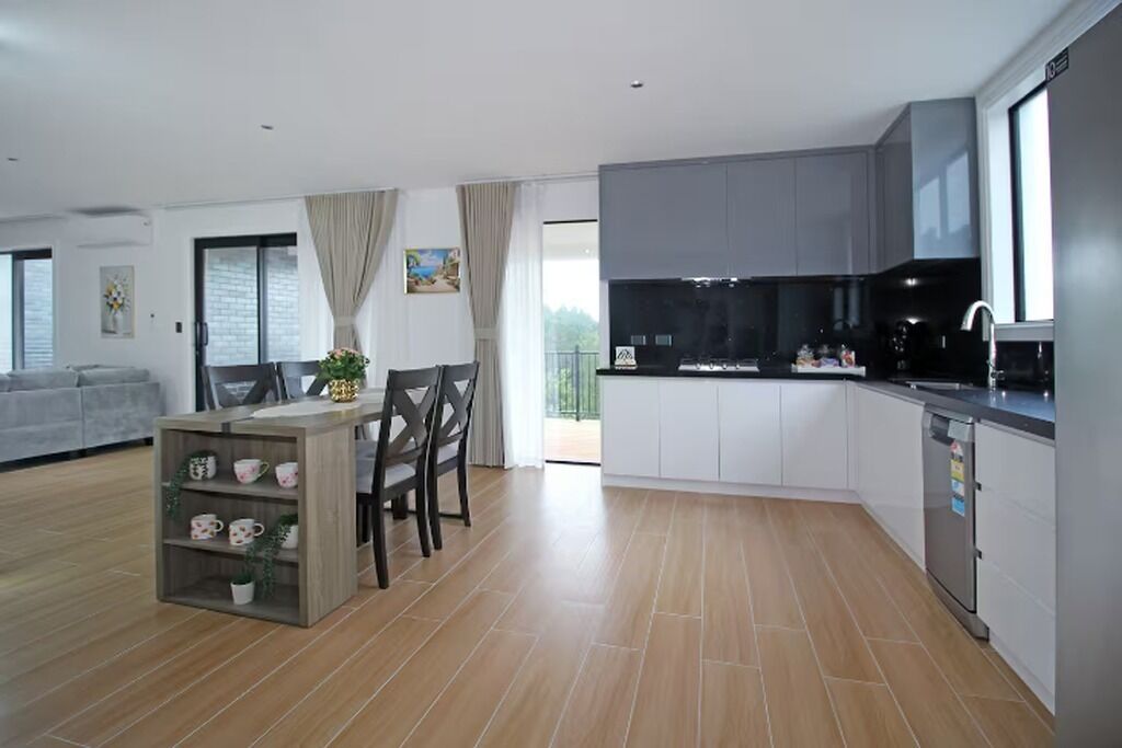 Una cocina moderna con armarios grises, una mesa de comedor de madera y un horno empotrado.