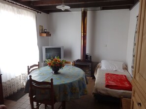 Ein Zimmer mit einem Bett, einem Tisch mit floraler Dekoration, einem Fernseher und einem Kaminofen.
