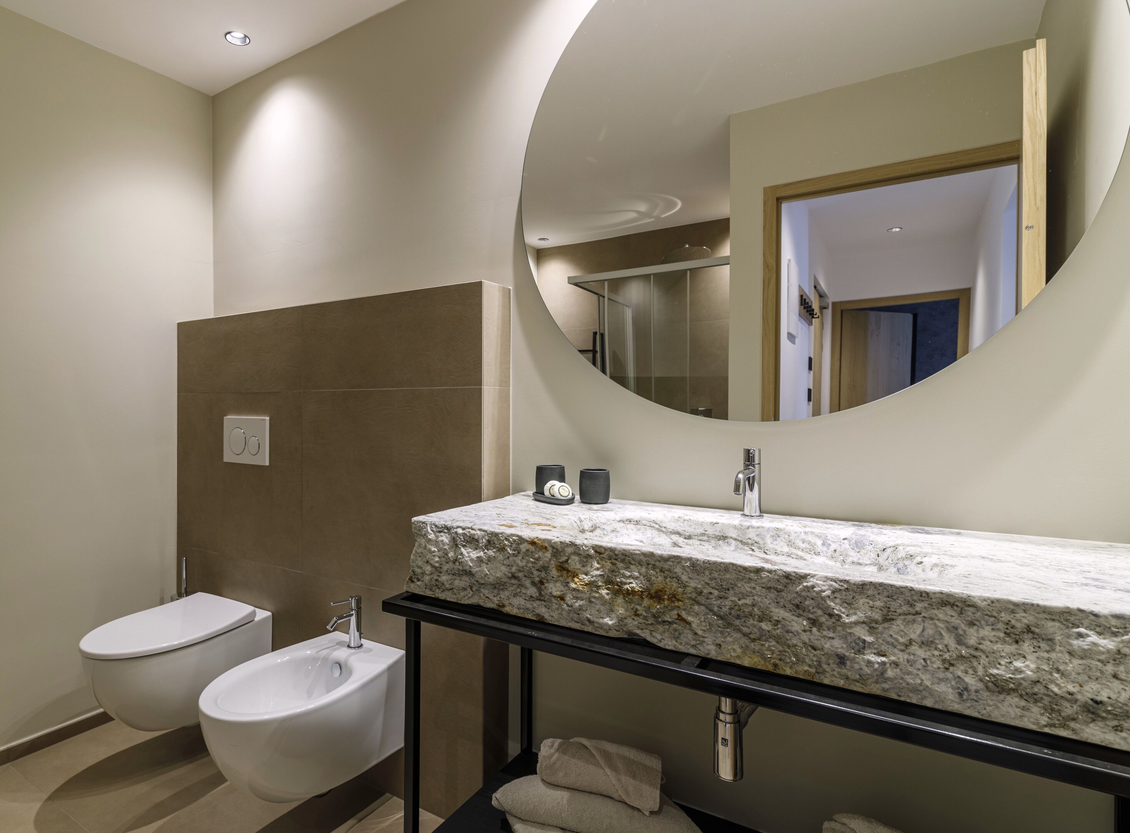 A bathroom with a marble sink, a toilet, a bidet, and a large mirror.