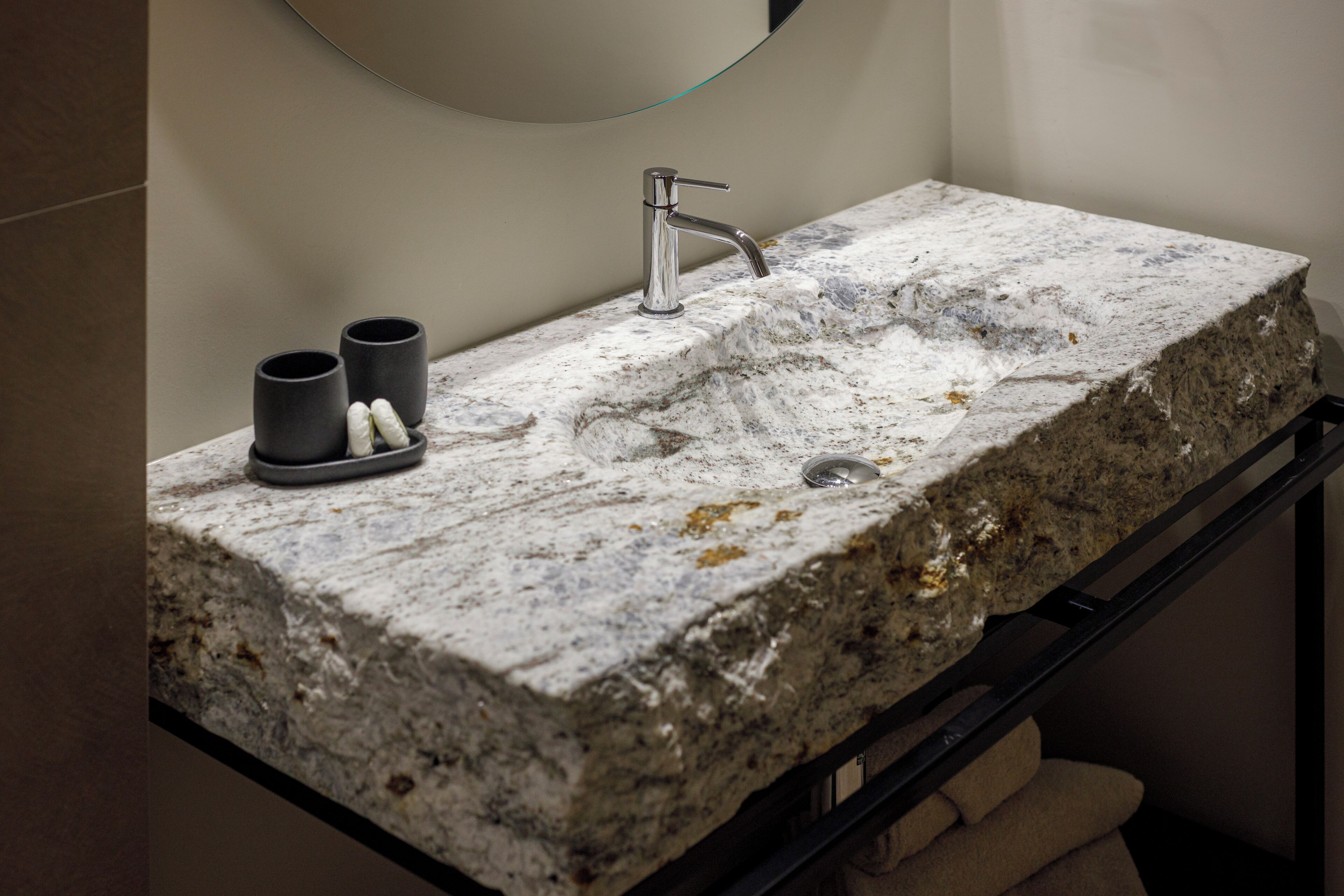 Un bagno con piano in granito, un rubinetto moderno e due tazze nere.