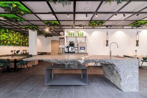 A modern interior with a large granite island, seating area, and a green wall with plants. - Boutique Hotel Sole (Vipiteno)