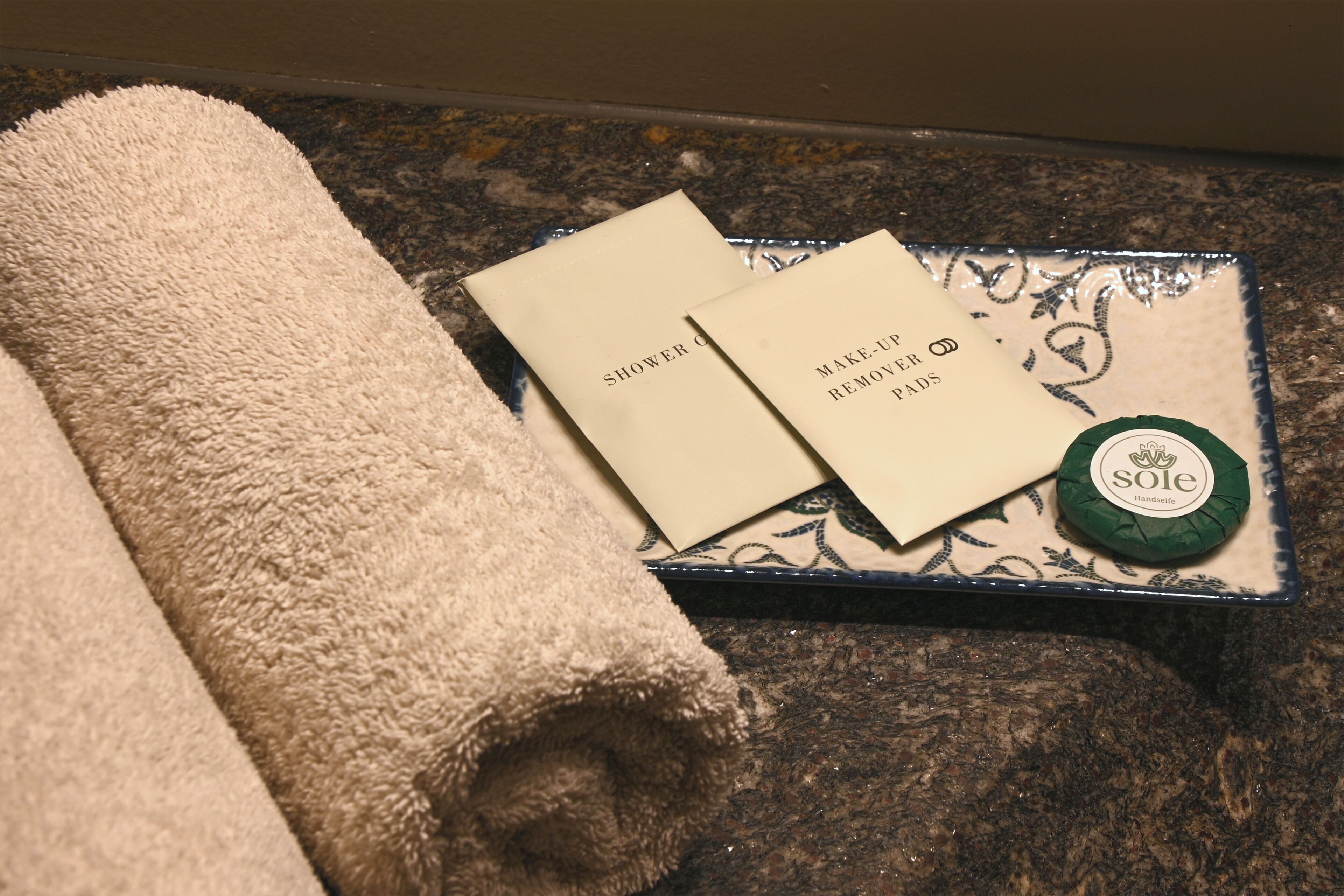 A towel, two cards, and a bottle on a countertop.