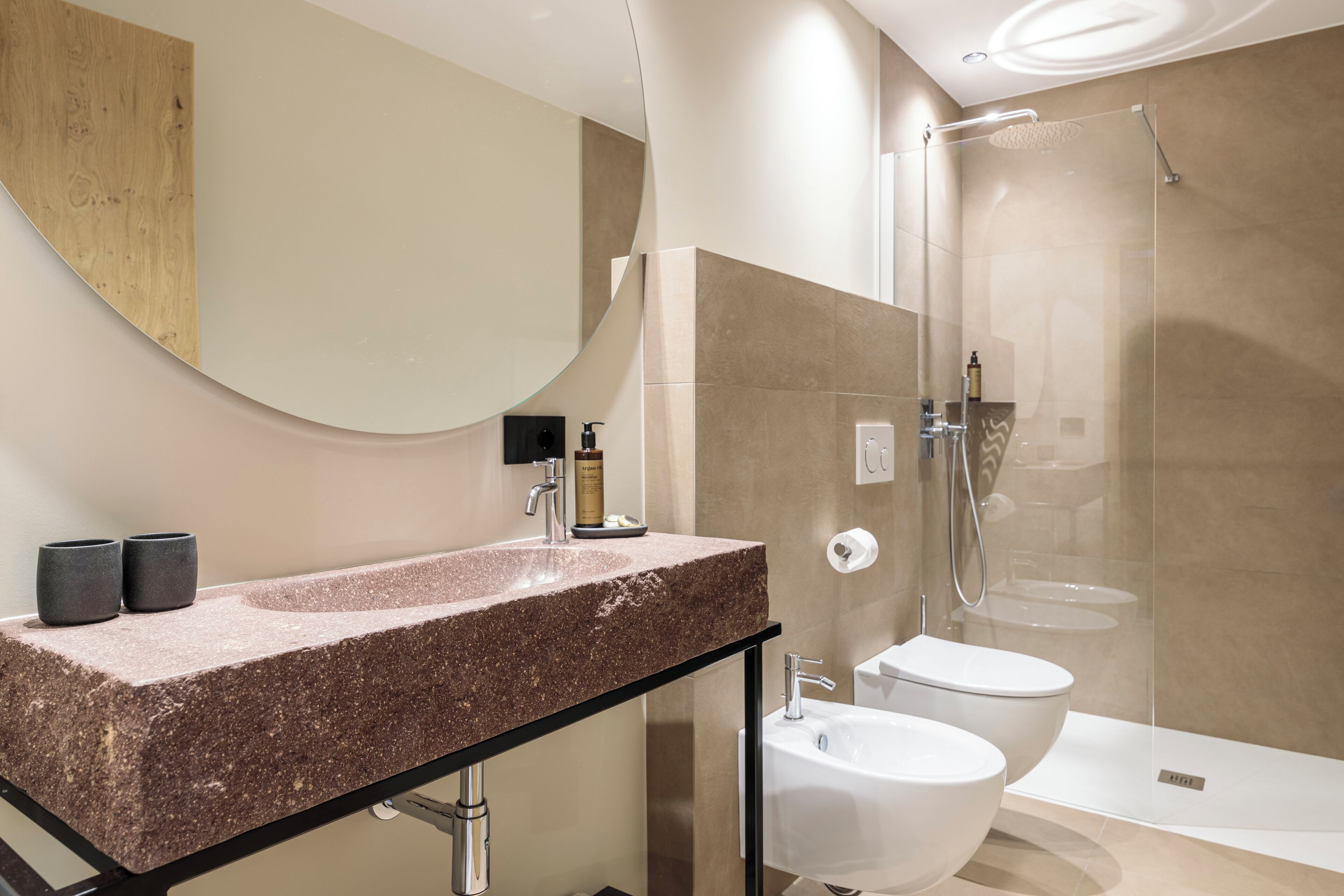 Ein modernes Badezimmer mit einem Granitwaschbecken, einer Toilette und einer Duschkabine.