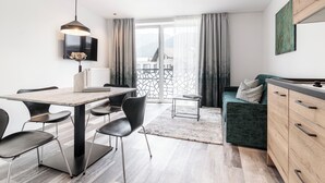 Ein stilvolles Wohnzimmer mit Essbereich, einer Couch, einem Fernseher und Blick ins Freie.