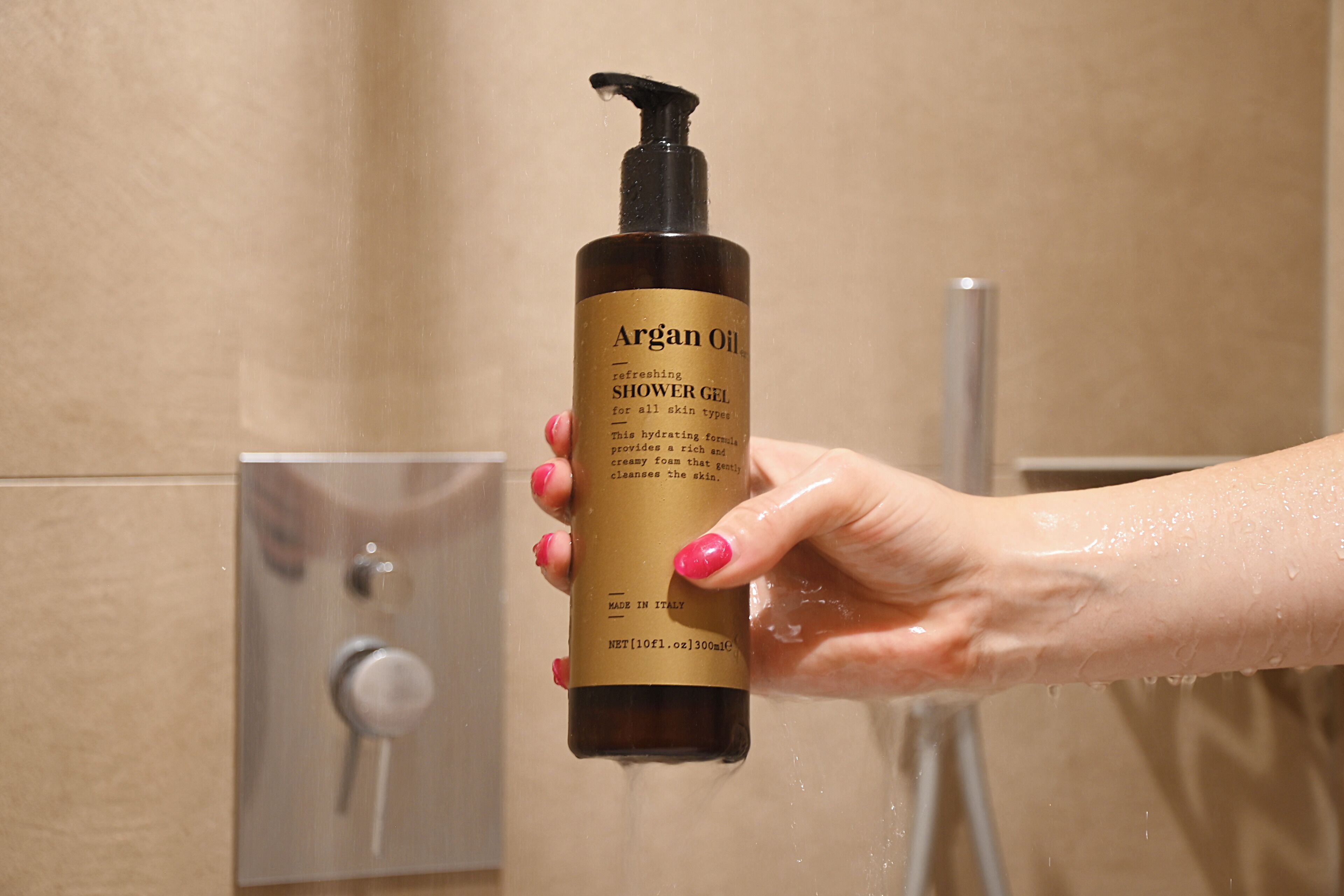 A hand holding a bottle of Argan Oil shower gel.