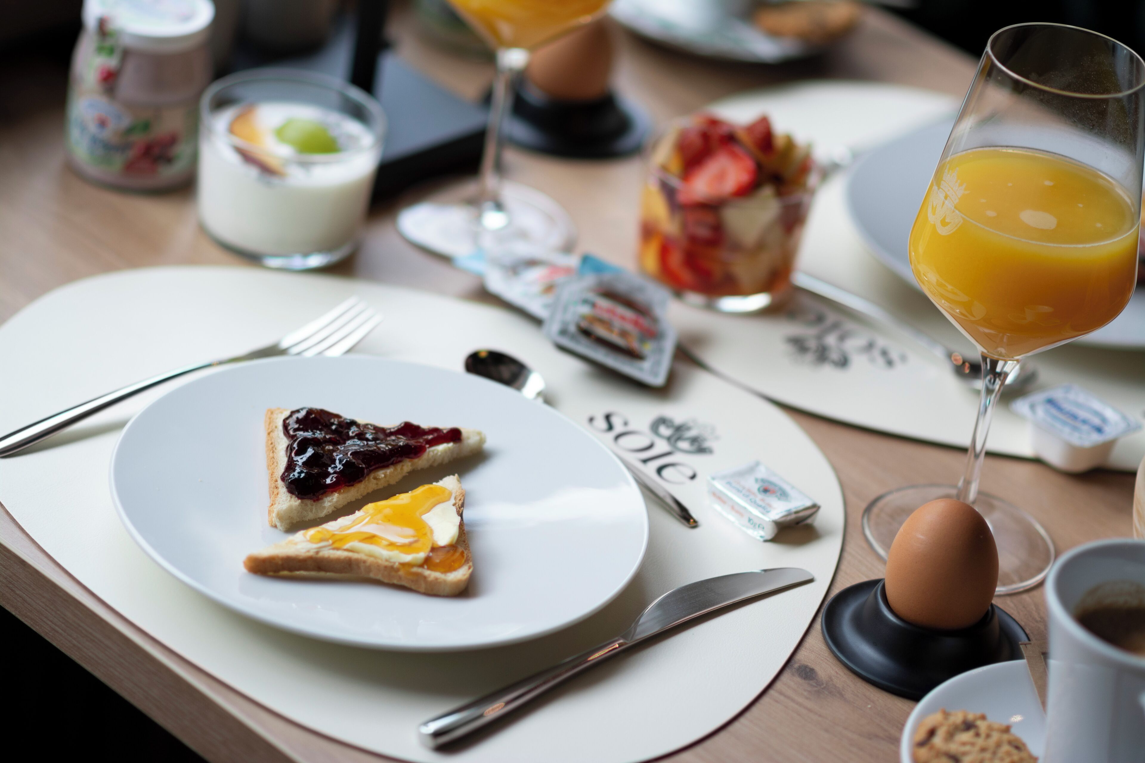 A breakfast setting with toast, a glass of orange juice, and a plate with jam and cheese.