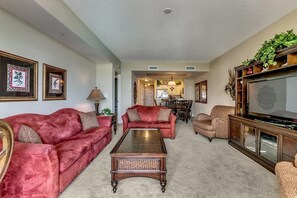 Ein Wohnzimmer mit einem roten Sofa, einem Couchtisch und einem Fernseher auf einer Holzkommode.
