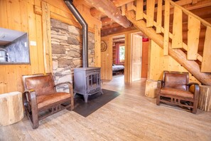 A wooden interior with a stone wall, a wooden staircase, and a fireplace. - Log cabin, close to the slopes, 8p (La Bresse)
