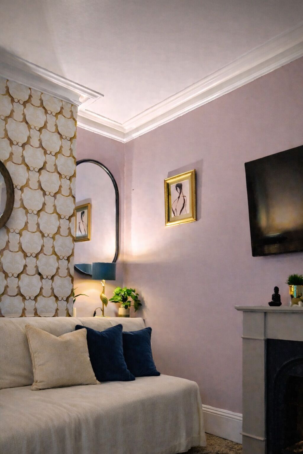 Un dormitorio con cama, espejo, televisor de pantalla plana y chimenea.