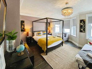 A four-poster bed with a yellow throw, bedside lamps, a globe, and a mirror on a dresser. - Bournemouth Beach Boutique with Hot Tub (Sleeps 14 and 5 mins walk to Beach) (Bournemouth)