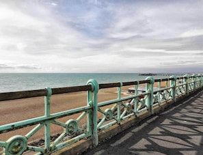 A coastal walkway with a metal railing, a sandy beach, and the sea in the background. - The Brighton Parlour with Hot Tub (Brighton)