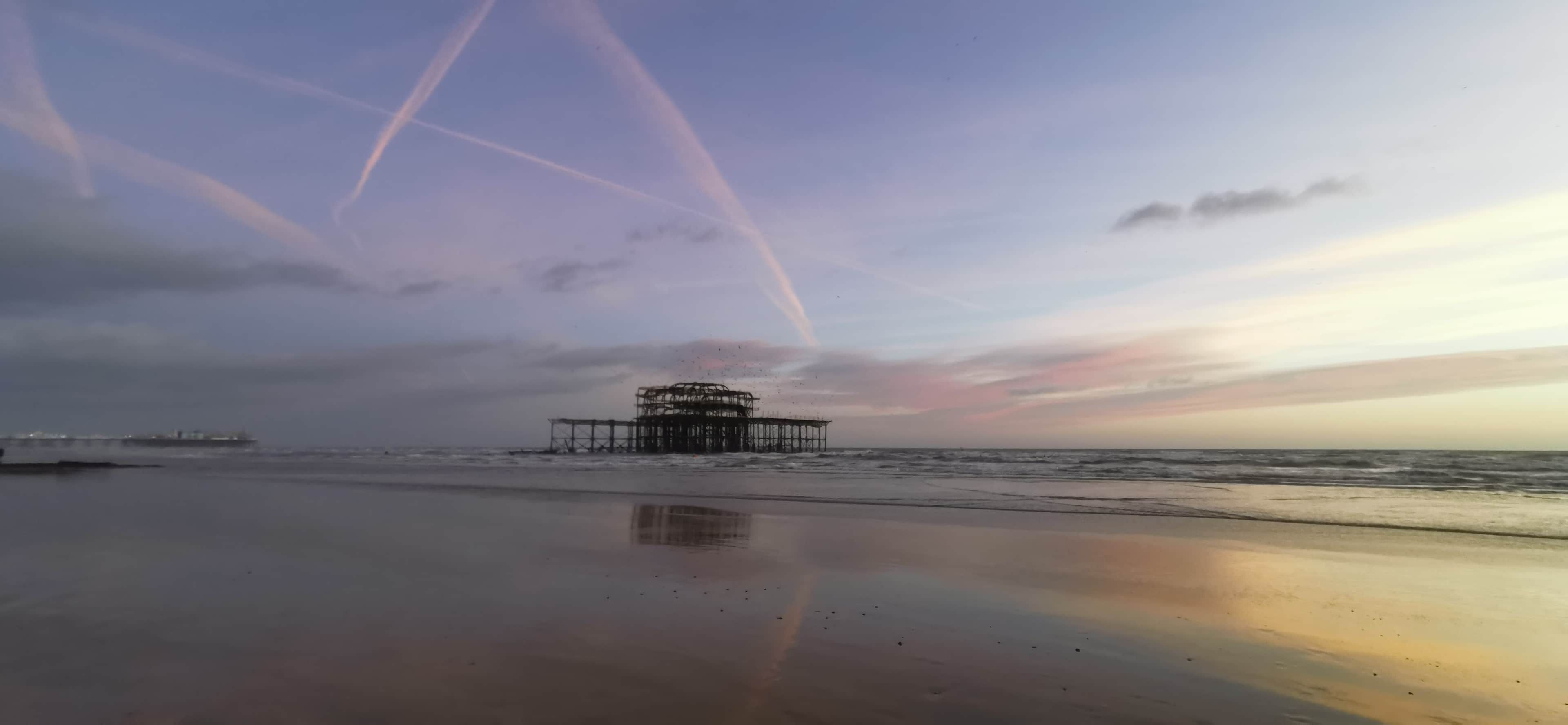 A beach with a pier extending into the water.